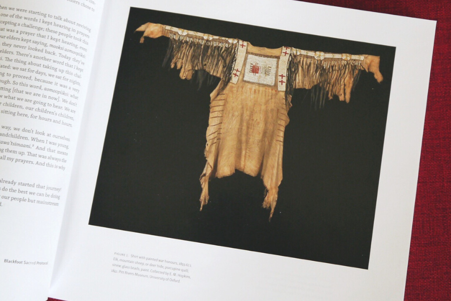 A photograph of a book containing a photograph of a Blackfoot hairlock shirt.